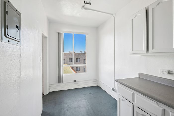 Bright utility room with sleek white cabinetry, a large window inviting natural light, and modern electrical features.