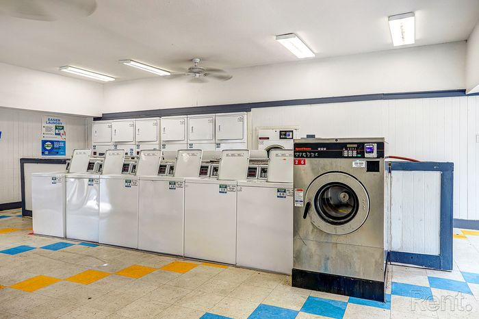 Bright and clean laundry room featuring multiple washing machines and dryers, with colorful floor tiles creating a welcoming atmosphere.