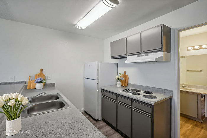 Modern kitchen with sleek gray cabinets, a white refrigerator, and elegant countertop featuring decorative flowers and cutting boards.