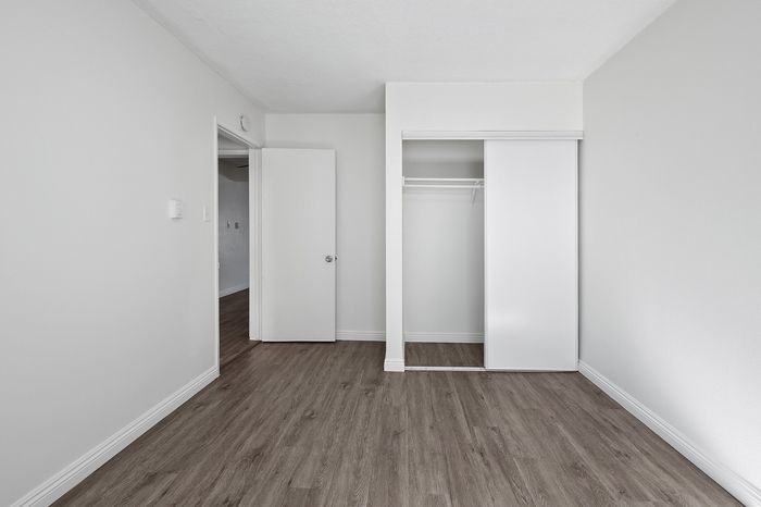 Bright and inviting empty room with sleek hardwood floors and a spacious built-in closet, perfect for customization.