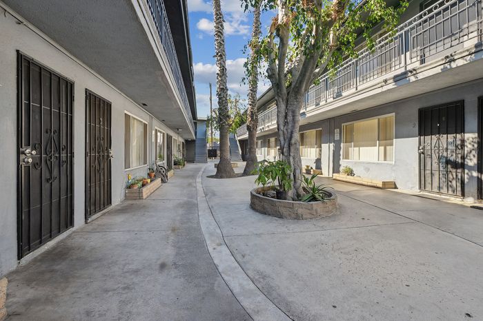 Charming courtyard view of a modern apartment complex with lush greenery and welcoming patios.
