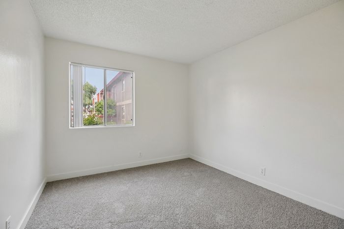 Bright and airy bedroom with plush carpeting and a large window offering charming outdoor views.