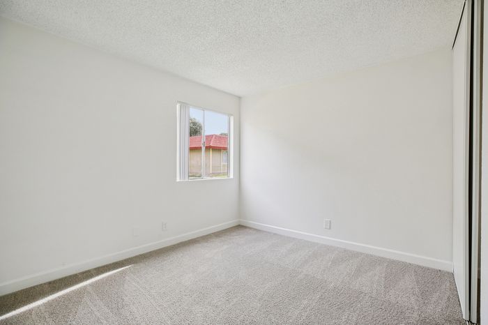 Sunlit room with soft carpet flooring and a large window offering a serene view, perfect for relaxation.