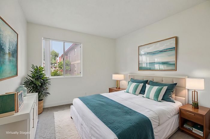 Bright and airy bedroom with modern decor, featuring a comfortable bed, elegant bedside tables, and a large window offering scenic views.