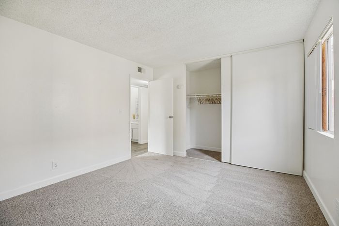 Bright, spacious bedroom with soft carpet flooring, large closet, and ample natural light.