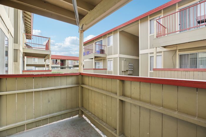 Charming apartment balcony offering a cozy outdoor space with views of elegant architecture and bright sky.