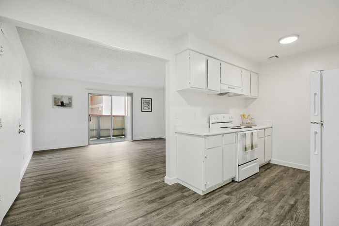 Bright and spacious open-plan living area with modern kitchen, elegant flooring, and large sliding glass doors for natural light.