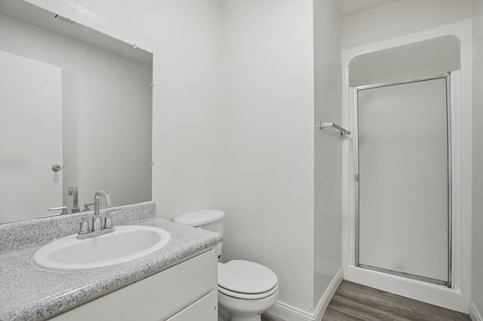 Bright and modern bathroom featuring a sleek granite countertop, sparkling fixtures, and a spacious shower area.