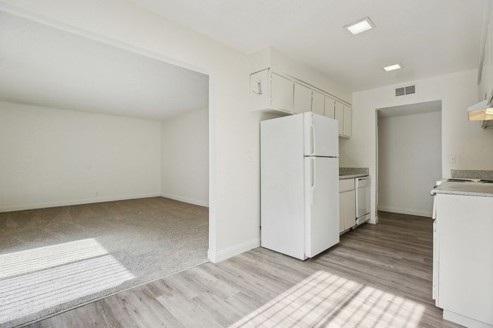 Bright and spacious kitchen with modern flooring, white cabinetry, and open access to living area.