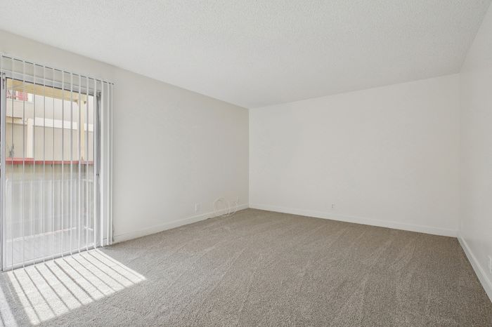 Bright, spacious room with plush carpet and large sliding glass doors offering natural light and an inviting atmosphere.