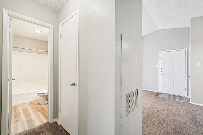 Bright apartment entrance featuring modern flooring, fresh paint, and a welcoming hallway leading to a stylish bathroom.