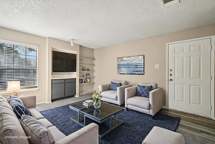 Virtually staged cozy living room with modern decor, plush seating, a large flat-screen TV, and abundant natural light streaming through the window.