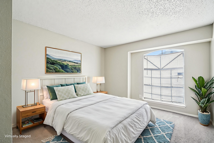 Bright and airy bedroom with a soft white color palette, featuring a cozy bed, elegant bedside lamps, and a large window letting in natural light, enhanced with virtual staging.