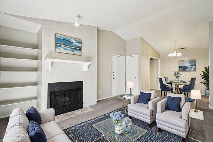 Chic living room with elegant furnishings, a cozy fireplace, open layout leading to a stylish dining area, perfect for modern living.