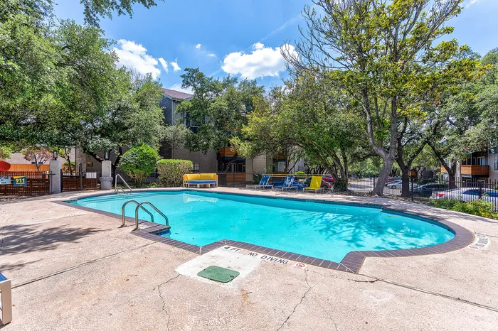 Charming outdoor pool area surrounded by lush greenery and comfortable lounging chairs, perfect for relaxation and leisure.