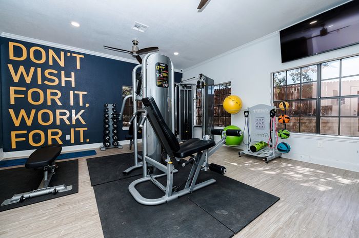 Inviting home gym with modern equipment, motivational wall quote, ample natural light, and sleek decor, perfect for energizing workouts.