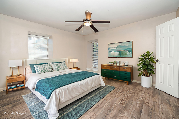 Inviting bedroom with modern decor, featuring a cozy queen-sized bed, sleek furniture, and a serene atmosphere complemented by natural light and stylish flooring.