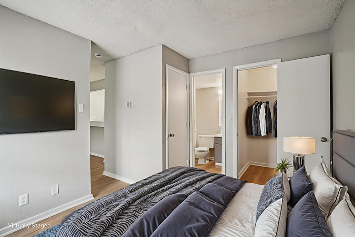 Cozy bedroom with modern decor featuring a wall-mounted TV, adjacent bathroom, and spacious closet.