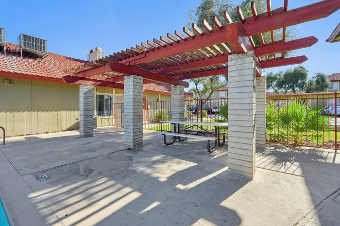 Inviting outdoor patio featuring a stylish pergola and modern picnic table, perfect for relaxation in a sunny courtyard.