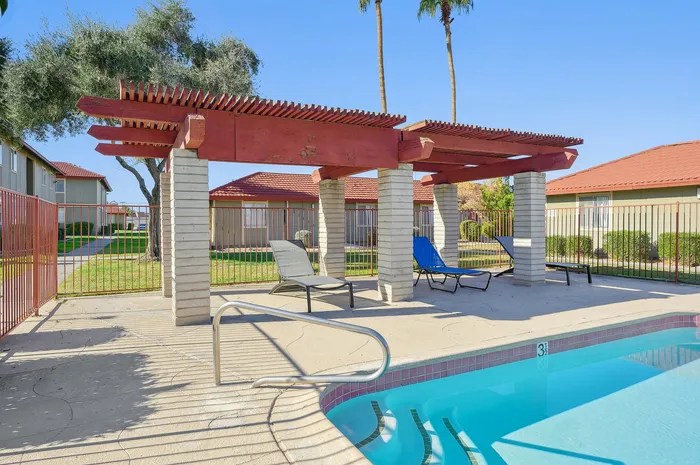 Inviting poolside oasis with stylish pergola and modern lounge chairs, perfect for relaxation and leisure.