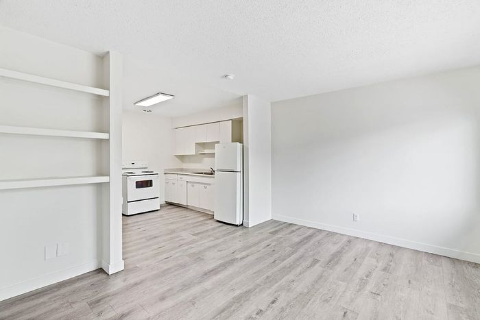 Bright and modern kitchen space with sleek white cabinetry, built-in shelving, and elegant flooring, perfect for seamless living and entertaining.