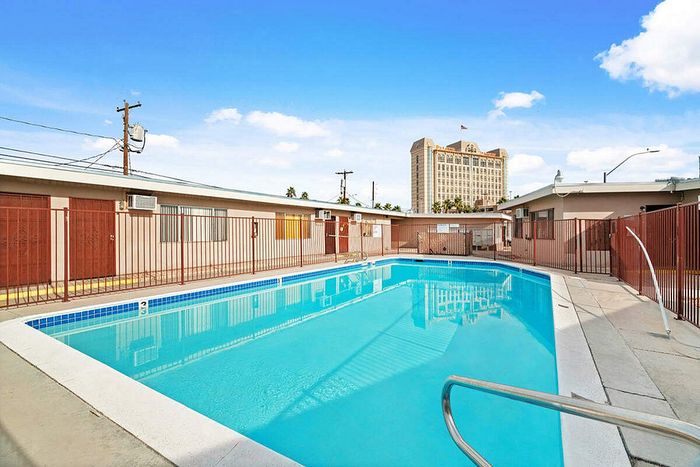 Inviting apartment complex with a sparkling pool and sunlit courtyard, offering a perfect urban escape.