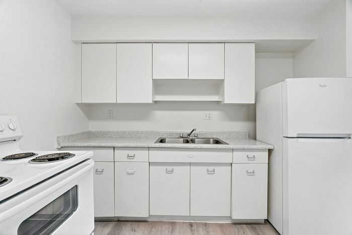 Bright modern kitchen featuring sleek white cabinets, a double-basin sink, and contemporary appliances, perfect for culinary creativity.
