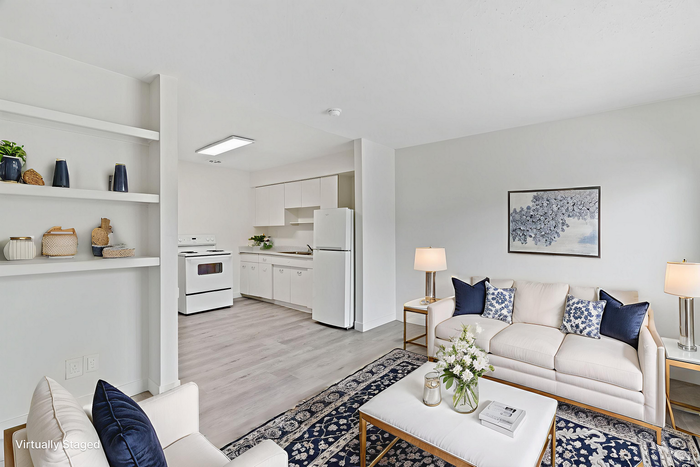 Chic open-plan living room and kitchen with elegant decor, featuring a cozy couch, modern furnishings, and abundant natural light.