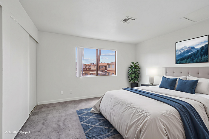 Inviting bedroom with modern decor, a cozy bed with blue accents, natural light, and a scenic view.