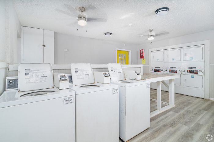 Modern and inviting laundry room with multiple washing machines, bright lighting, and a clean, spacious layout.
