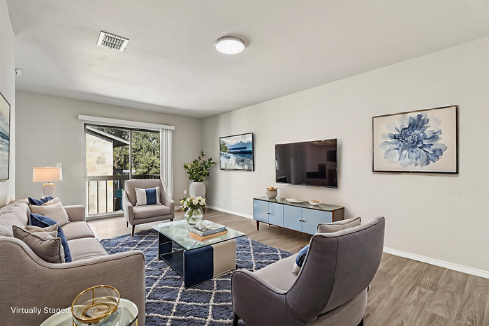 Elegant living room showcasing modern design, featuring plush seating, a sleek TV, and abundant natural light from a large window with scenic views.