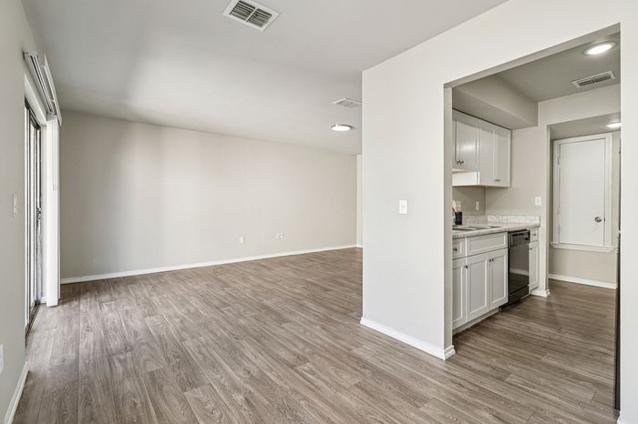 Spacious open-plan living area with modern wooden flooring, abundant natural light, and a sleek kitchen with white cabinetry and stainless steel appliances.