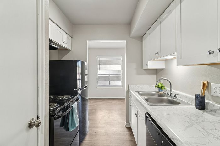 Bright and modern kitchen with sleek black appliances, white cabinetry, and elegant marble countertops.