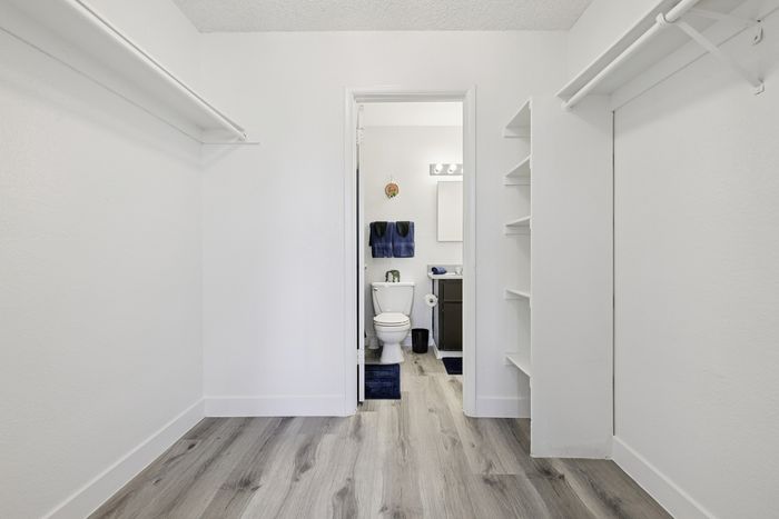 Sleek walk-in closet with ample shelving, leading to a modern bathroom featuring contemporary fixtures and elegant accents.