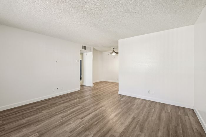 Bright and spacious living area with elegant wood flooring and modern ceiling fan, perfect for stylish living.