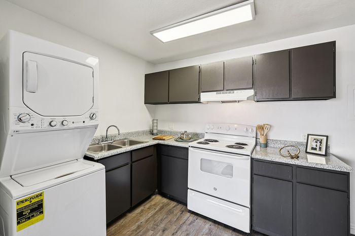 Modern kitchen with sleek dark cabinets, a contemporary electric stove, and in-unit washer and dryer, perfect for a convenient lifestyle.