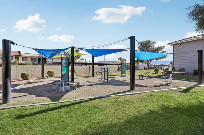 Inviting outdoor fitness area with modern exercise equipment and vibrant shade sails on a sunny day, perfect for a refreshing workout amidst serene surroundings.