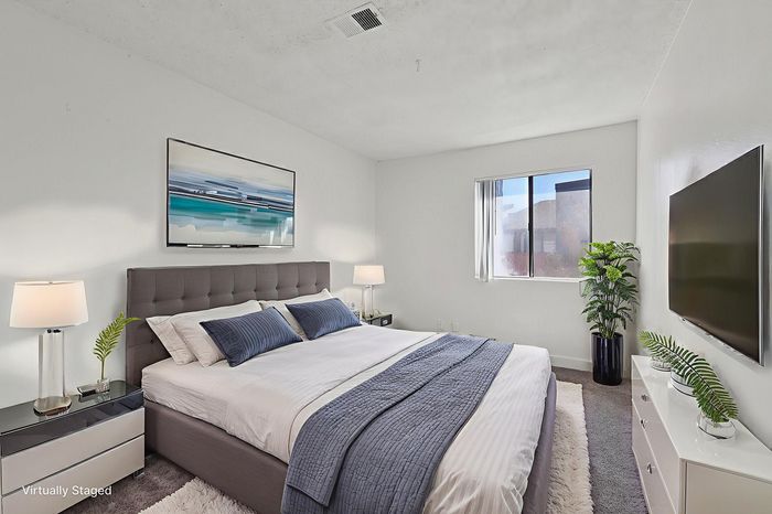 Elegantly staged bedroom with a cozy bed, modern decor, and abundant natural light.