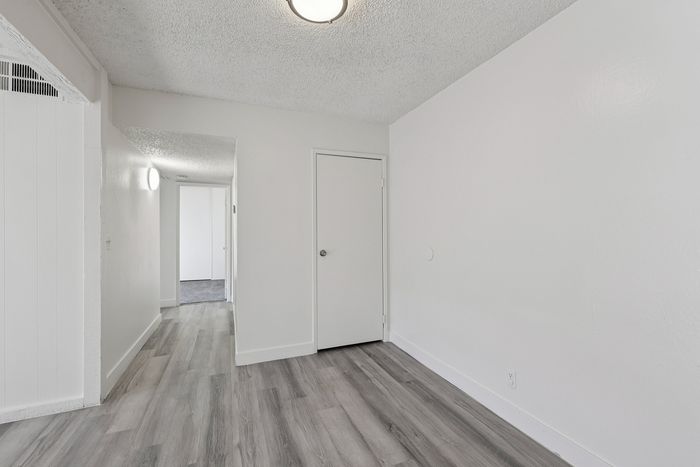 Bright, modern hallway with sleek light wood flooring, leading to a spacious room, perfect for elegant living.