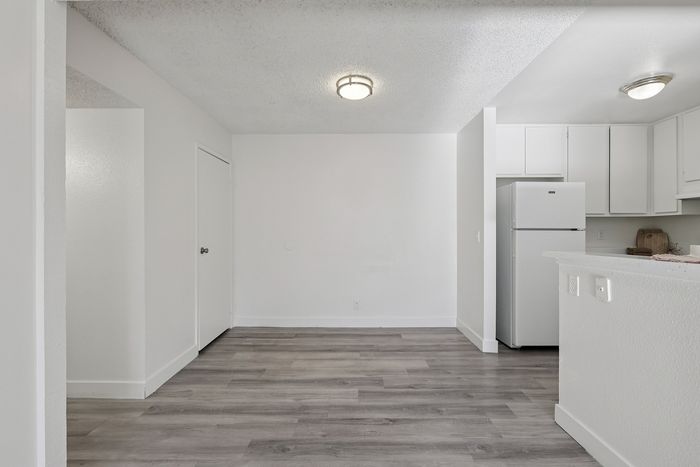 Modern open-concept space showcasing sleek flooring, bright kitchen, and ample natural light.