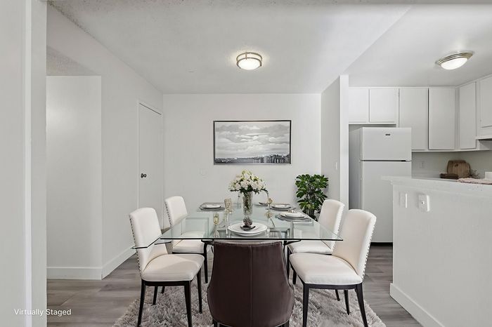 Elegant dining area with a glass table, modern chairs, and chic decor in a bright apartment setting.