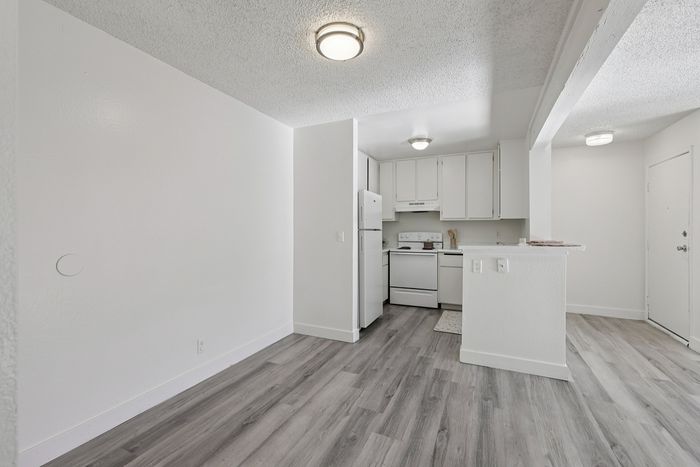 Bright and inviting open-concept kitchen with modern white cabinetry and sleek flooring, ideal for cozy living.