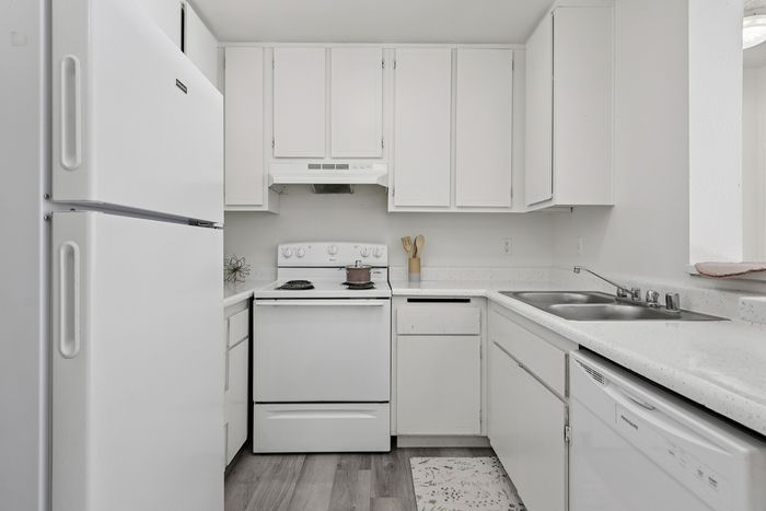 Bright and modern kitchen featuring sleek white cabinetry, spacious countertops, and stainless steel appliances.