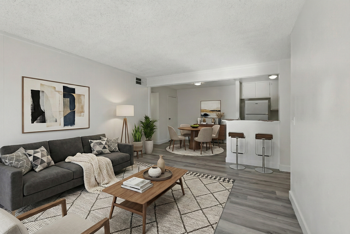 Elegant open-plan living area with modern decor, featuring a cozy lounge, stylish dining space, and contemporary kitchen with sleek stools.