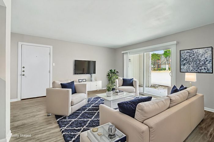 Stunning modern living room with elegant beige sofas, a chic blue area rug, and abundant natural light from large sliding doors.