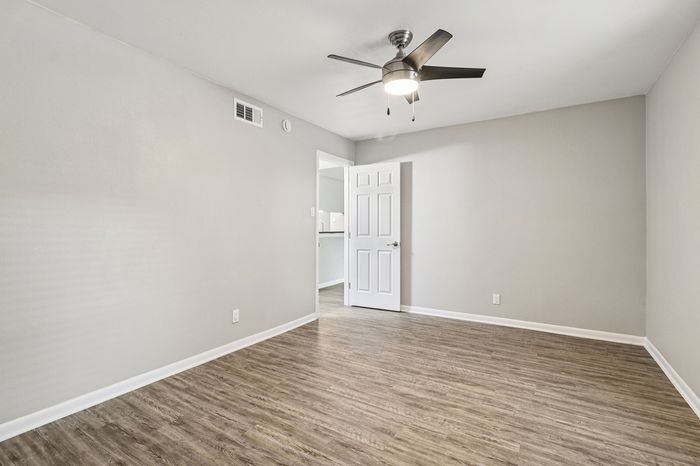 Bright, spacious room featuring sleek wooden flooring and a modern ceiling fan, ideal for stylish living.