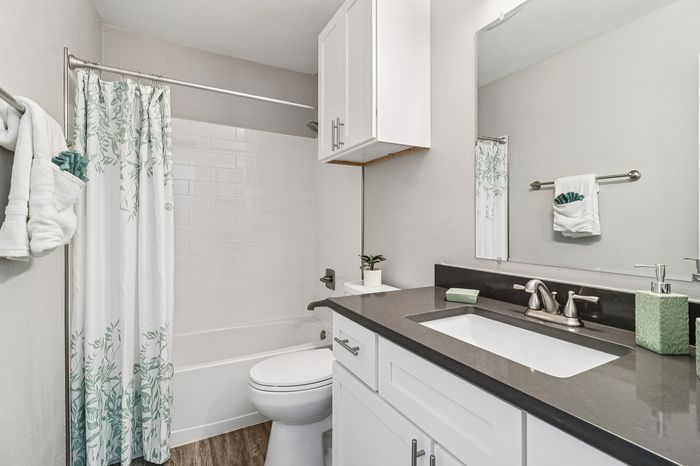 Elegant bathroom with modern fixtures, featuring a sleek vanity, stylish shower curtain, and chic tile accents creating a spa-like ambiance.