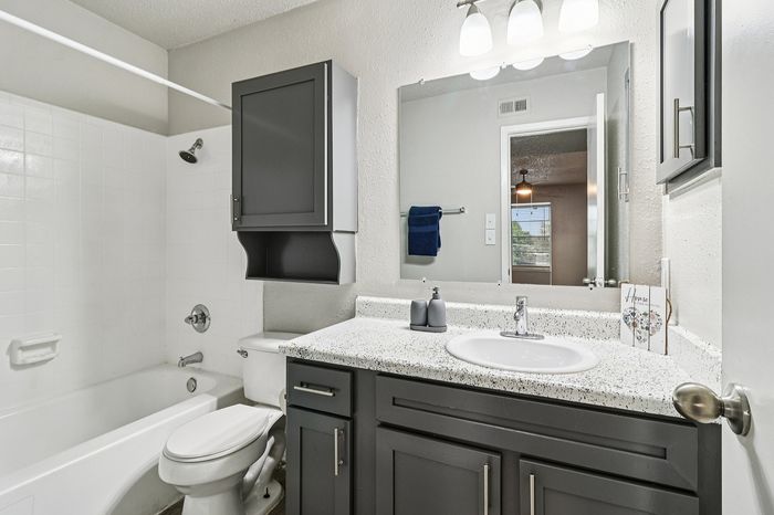 Elegant bathroom with modern fixtures, stylish vanity, and a spacious mirror reflecting natural light.