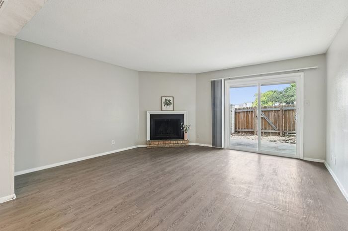 Bright, spacious living room with elegant fireplace and large glass doors leading to a sunny patio.