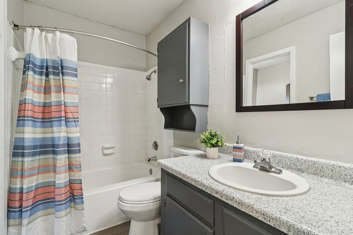 Bright, modern bathroom with sleek granite countertop, stylish dark cabinetry, and a vibrant striped shower curtain.